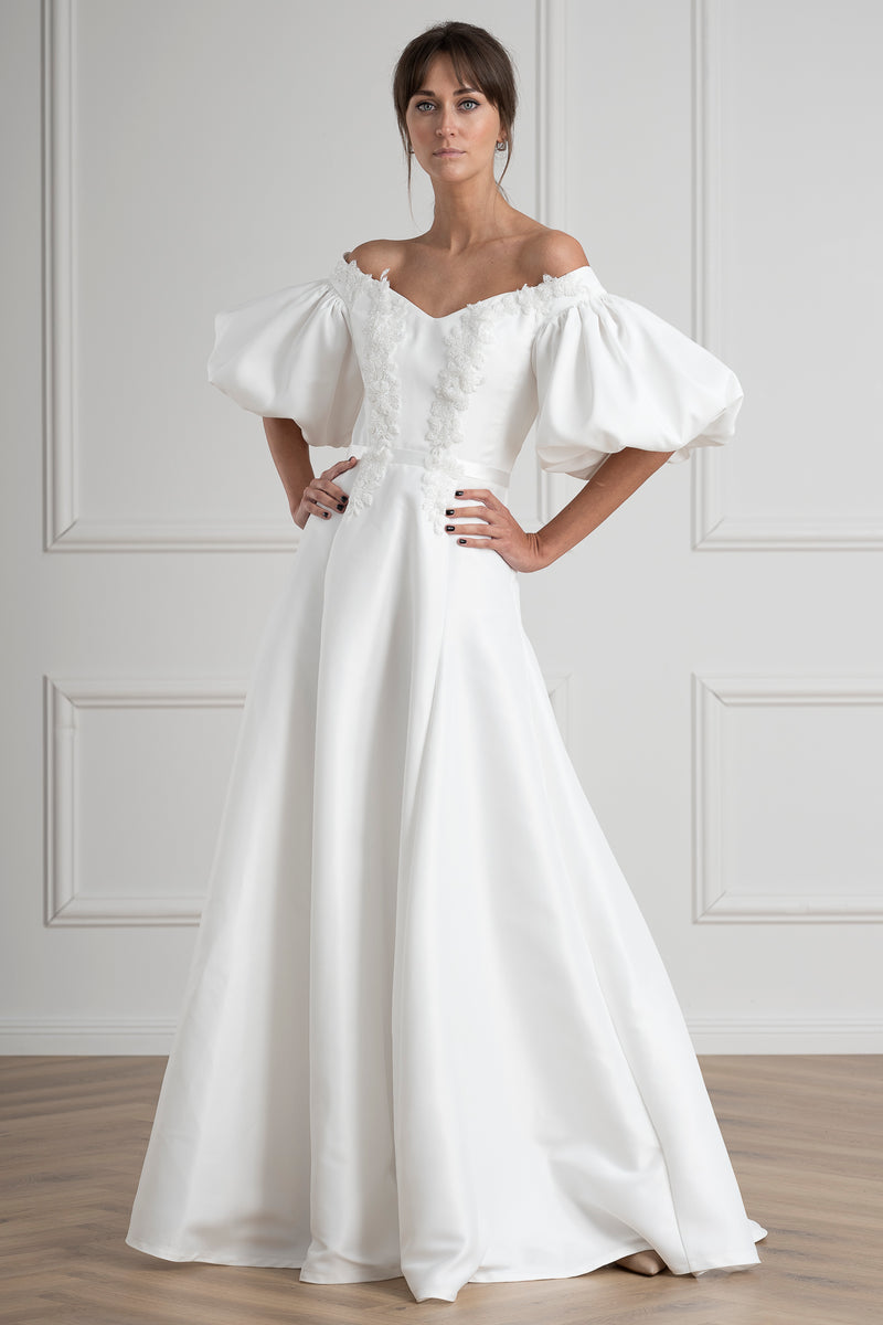 Woman wearing a white off-shoulder dress with puffed sleeves against a light gray wall. kāzu salons Rīgā
kāzu salons Rīgā,kāzu kleitas Rīgā,līgavu salons,dizaina kāzu kleitas,pieraksts uz pielaikošanu,līgavas tēls,modernās kāzu kleitas,minimālisma kāzu kleitas,mežģīņu kāzu kleitas,elegantas kāzu kleitas,ekskluzīvas kāzu kleitas,kāzu kleitu pielaikošana,līgavas kleita,kāzu kleitu veikals,kāzu mode Latvijā,bridal salons Riga,kāzu salons centrā Rīgā,Alberta iela kāzu salons,kāzu kleitas Latvijā,līgavu kleitas 