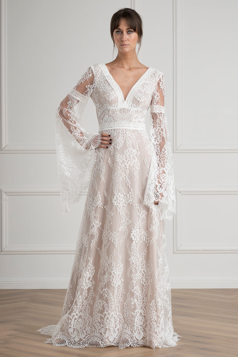 boho bride wearing a lace wedding dress against nude wedding dress ivory weding dress boho style bride vintage wedding dress classic bride elegant wedding dress long sleeve wedding dress